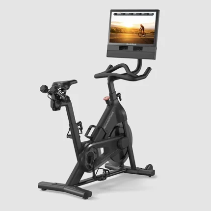 A person cycling on the Bike NEW S24 Studio NordicTrack, showing its large 24-inch touchscreen display