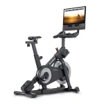 A person cycling on the Bike NEW X24 NordicTrack, showing its large 24-inch touchscreen display during an iFIT workout