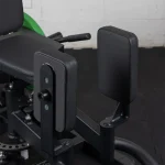 A person demonstrating a Plate Loaded Hip Abductor And Adductor exercise, pushing their legs outward against the pads